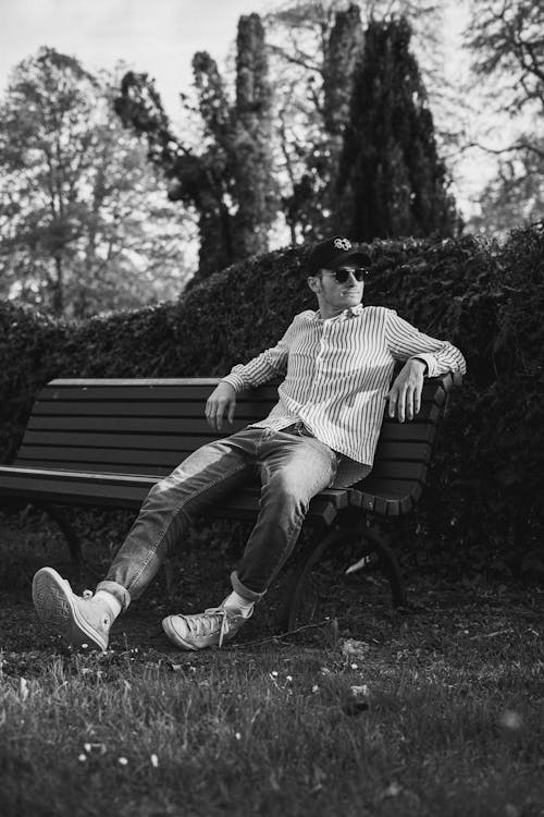 Grayscale Photo of a Man Sitting on a Bench