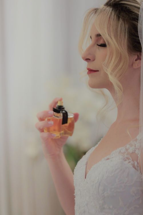 Free Close-up of a bride in wedding dress elegantly spraying perfume, captured indoors. Stock Photo