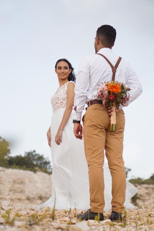 Man Holding a Flower Behind her Back for a Woman