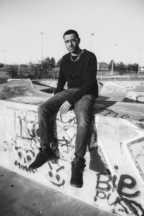 Free Black and white portrait of a man sitting at a skate park, exuding cool style. Stock Photo