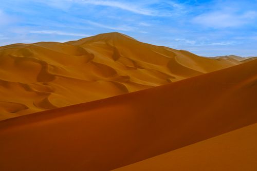 Free Captivating sand dunes in a desert landscape beneath a vibrant blue sky, showcasing natural textures. Stock Photo