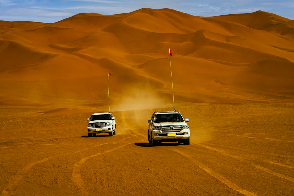 Two SUVs traverse vast desert dunes, capturing the thrill of off-road travel.