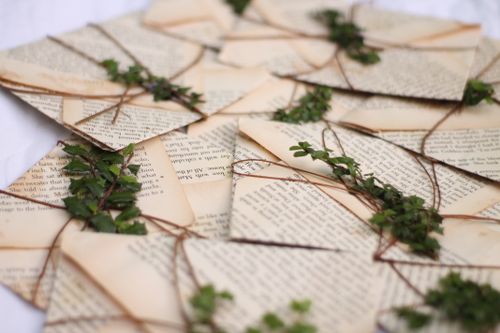Free Artistic arrangement of vintage book pages tied with twine and adorned with natural greenery. Stock Photo