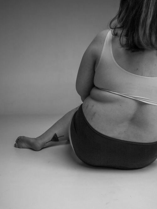 Free Black and white studio portrait celebrating body positivity with a plus-size woman sitting. Stock Photo