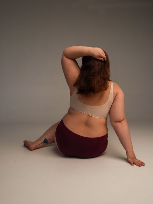 Free Back view of a plus size woman sitting in a studio, embracing body positivity. Stock Photo