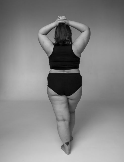 Free Black and white studio shot of a plus-size woman embracing her body with confidence. Stock Photo