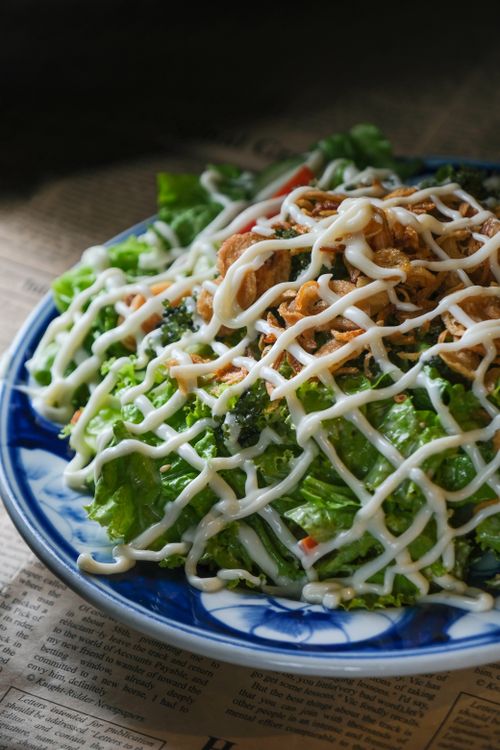 Free A vibrant leafy green salad drizzled with mayonnaise and topped with crispy fried shallots. Stock Photo