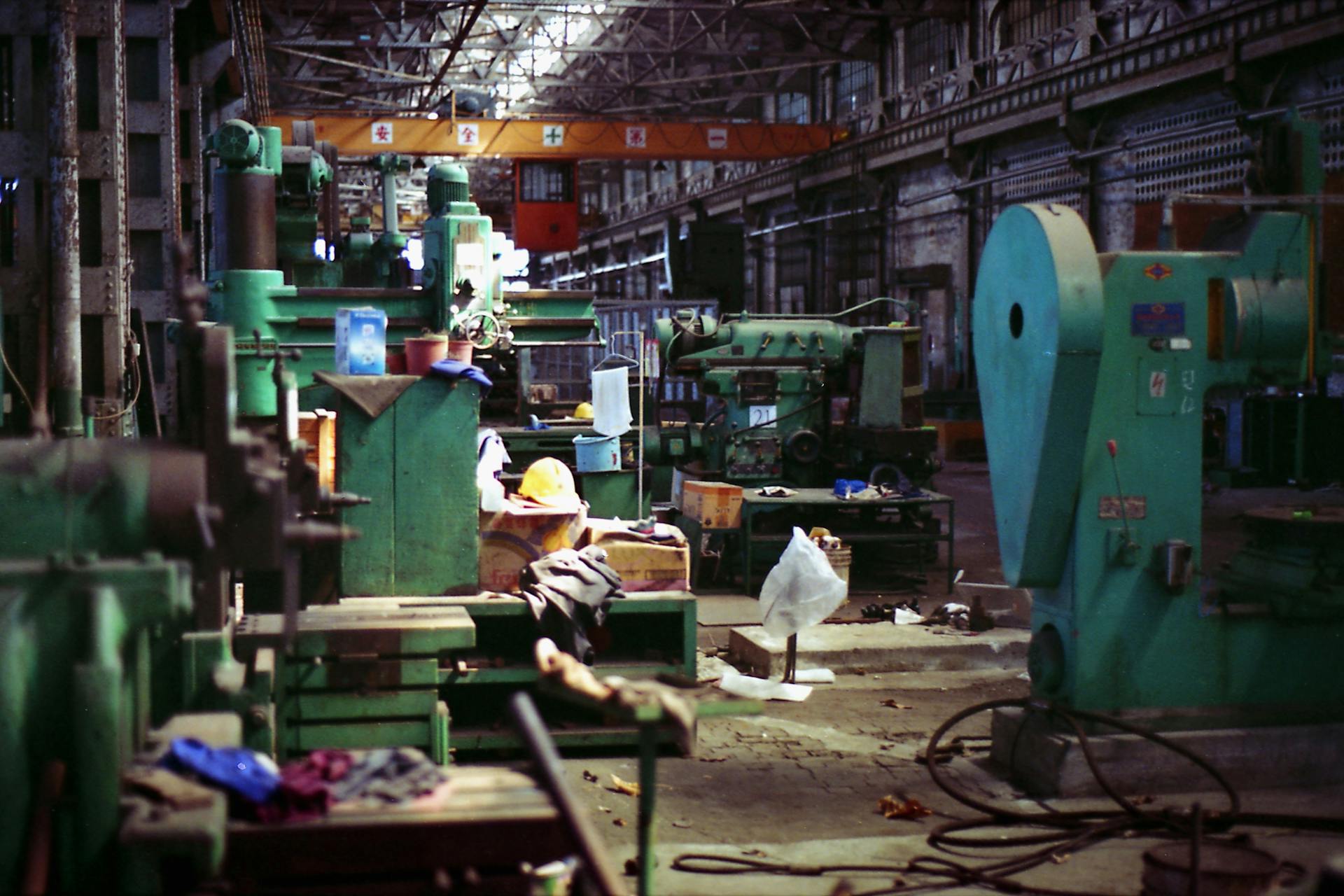 A spacious, dimly lit industrial factory filled with old machinery in Taipei City.