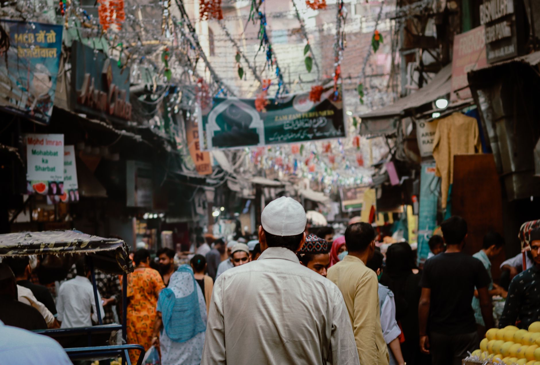 Crowded lane of Chandni Chowk with shop signs, wires and cycle rickshaws in Old Delhi