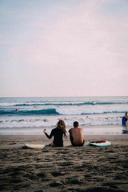 Couple Sitting on the Sand in the Beach