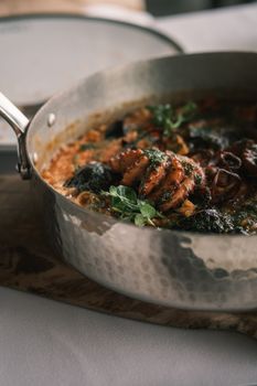 Close-up of gourmet seafood pasta with herbs in an artisan copper pan, perfect for food lovers.