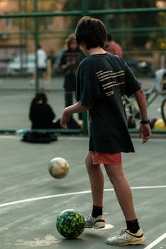 A teenager playing soccer casually on an outdoor court in Istanbul during daytime.
