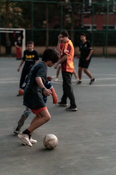 Boys energetically playing soccer on an outdoor court in İstanbul, showcasing youthful skill and teamwork.