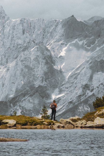 A stunning view of a backpacker near a serene lake in a mountain landscape.