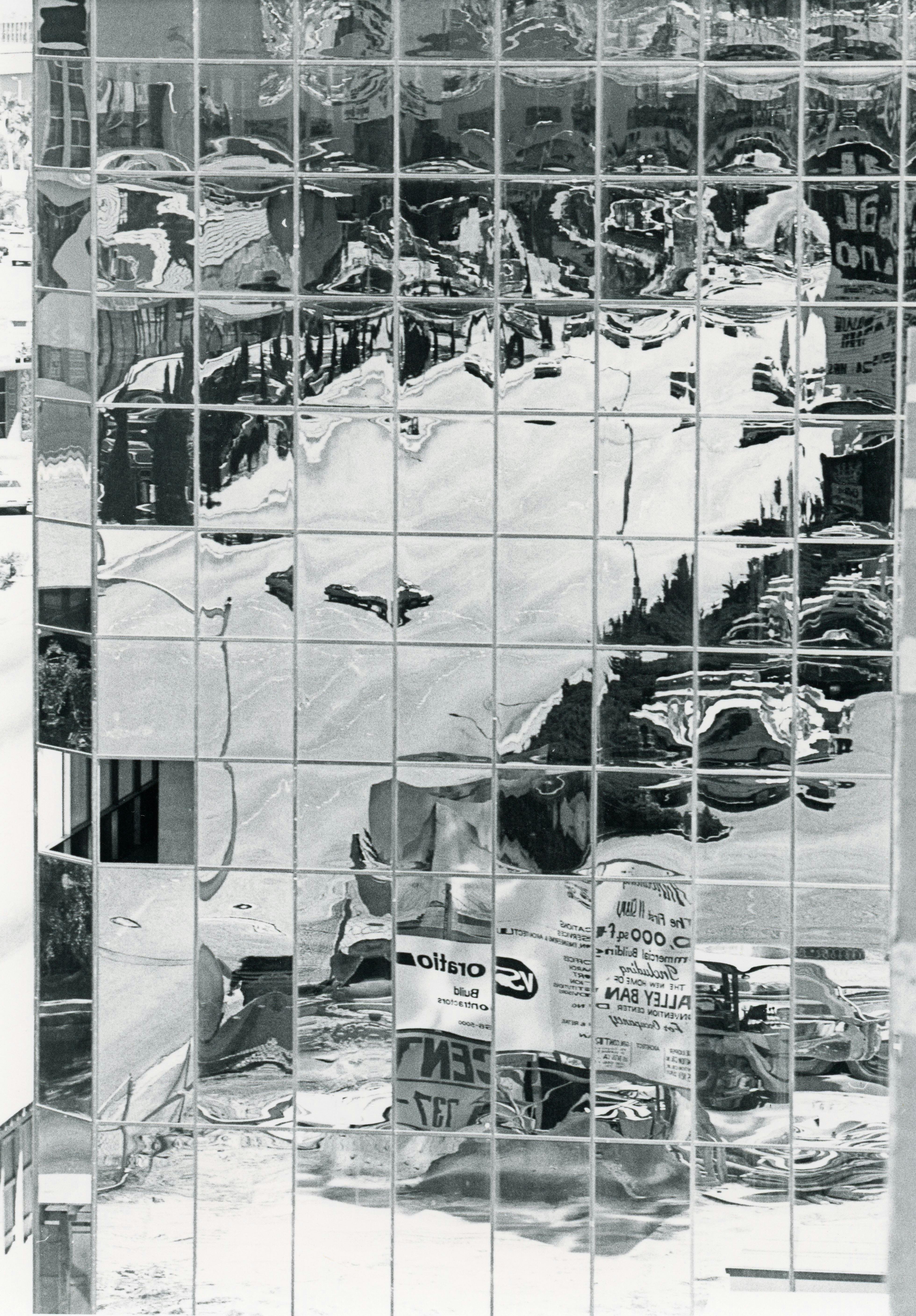 Distorted reflections of an urban scene in a glass building facade.