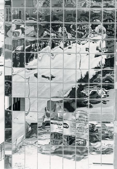 Distorted reflections of an urban scene in a glass building facade.