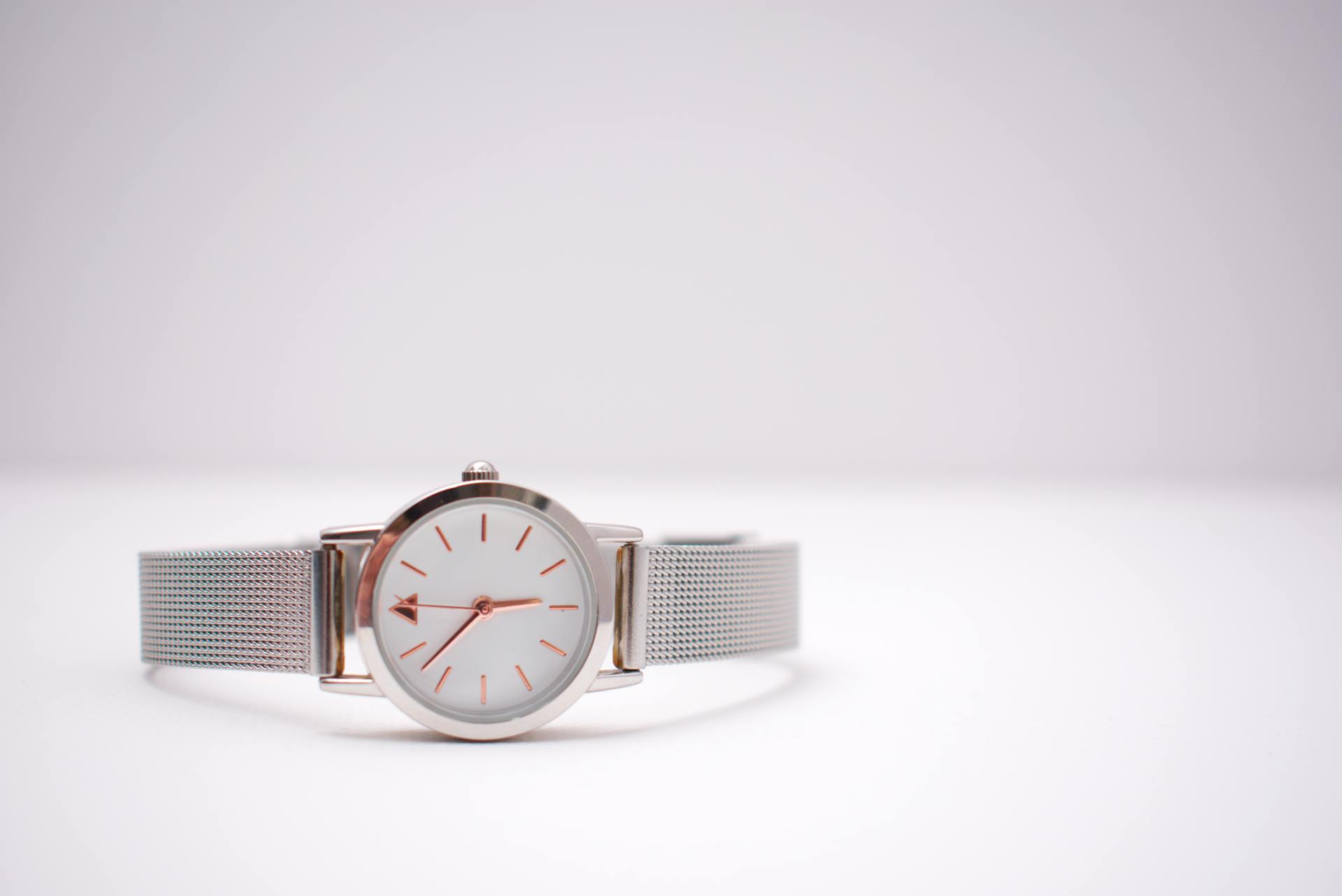 Close-up of a silver wristwatch with precision details on a minimalist background.