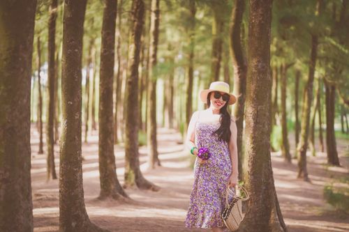 Free A fashionable woman in a floral dress and sun hat enjoying a sunny day in the forest. Stock Photo