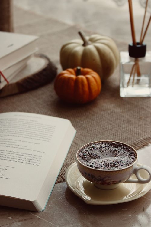 Free A warm and cozy autumn scene with a cup of coffee, book, and pumpkins. Stock Photo