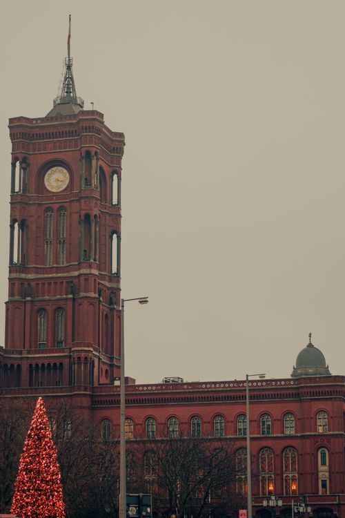 Free Red brick building with a clock tower and a Christmas tree in a foggy winter setting. Stock Photo