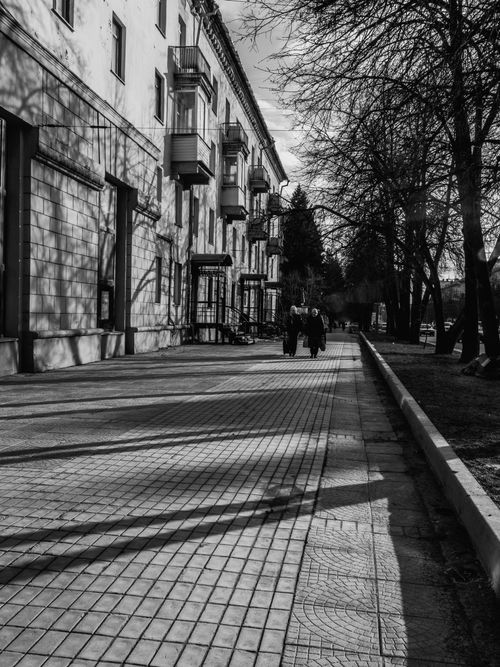 Free A black-and-white photo of a quiet city street with people walking. Stock Photo