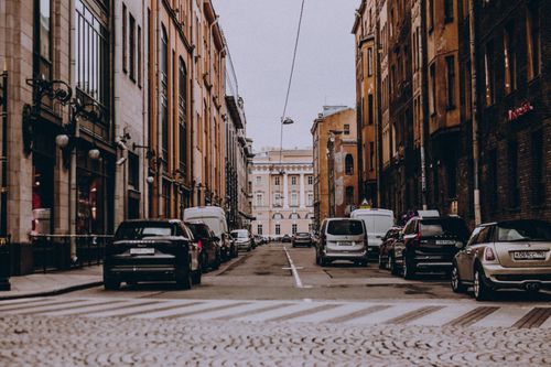 Free Scenic view of a narrow city street with parked cars lined by historic architecture, ideal for urban themes. Stock Photo