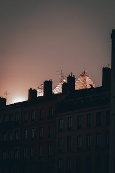 A dramatic view of Lyon's silhouetted rooftops against a warm dawn sky.
