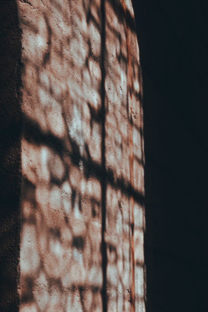 Lattice shadow cast across a sunlit stone wall, by Ryan Klaus on Pexels