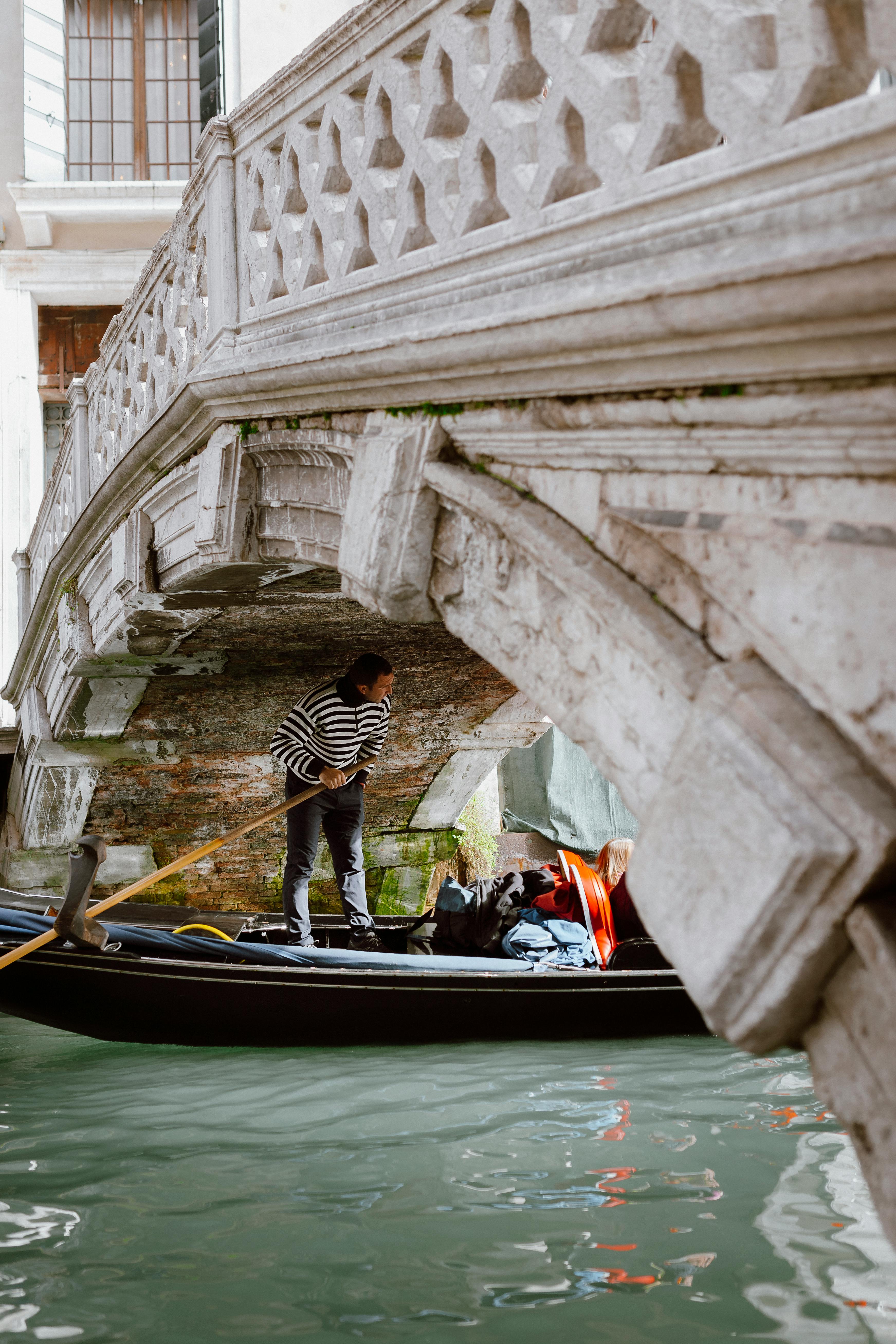gondolier in gondola under bridge