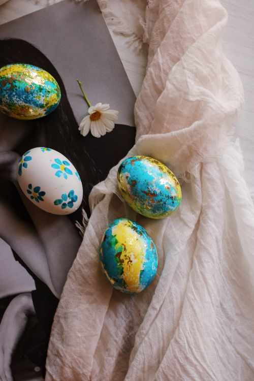 Free Colorful painted Easter eggs on gauzy fabric with a daisy accent. Stock Photo