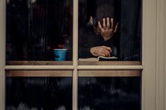 A man sits with hand on face at a window in Istanbul, exuding deep contemplation.