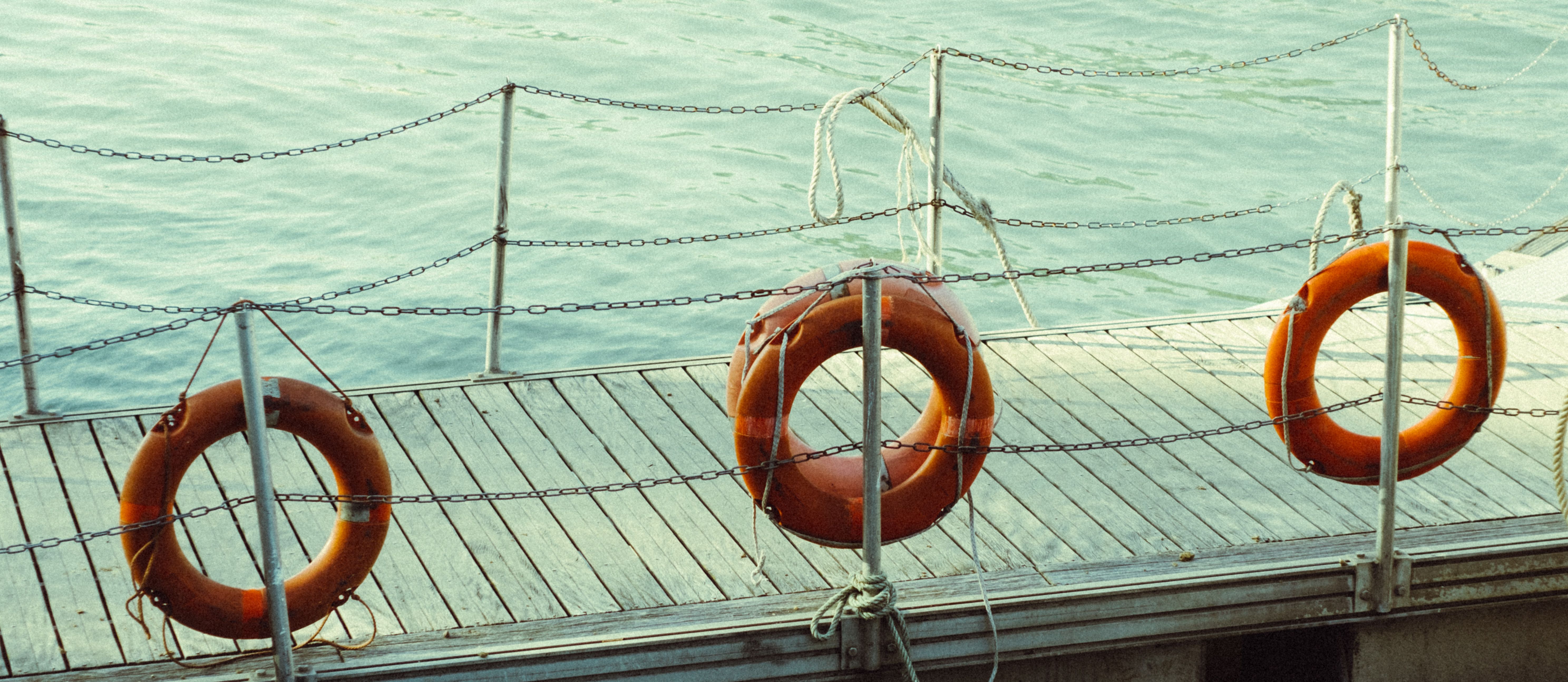 Three life rings hang on a dock by the tranquil sea, providing a sense of safety and readiness.