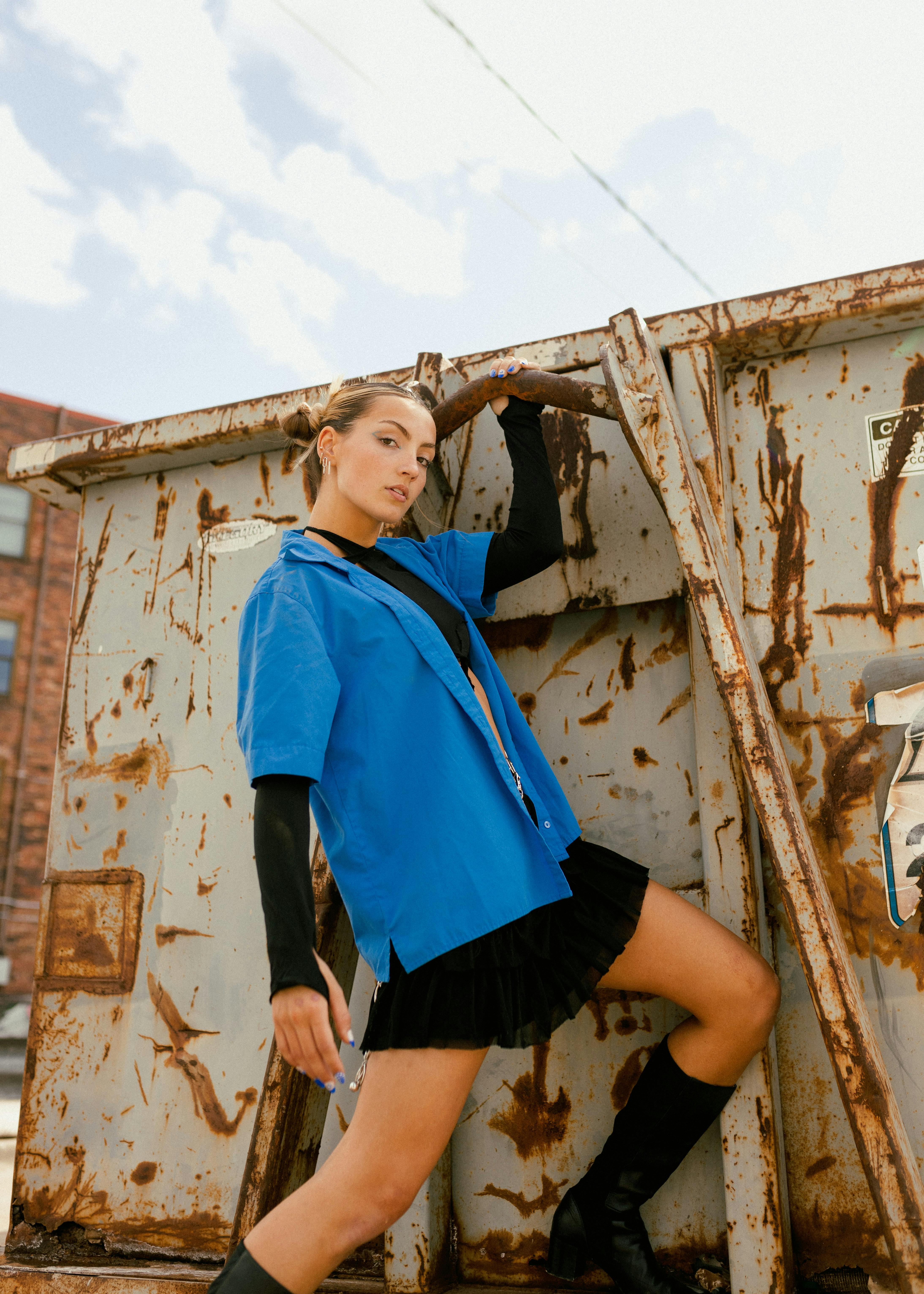 a woman wearing a blue short sleeved shirt and black skirt