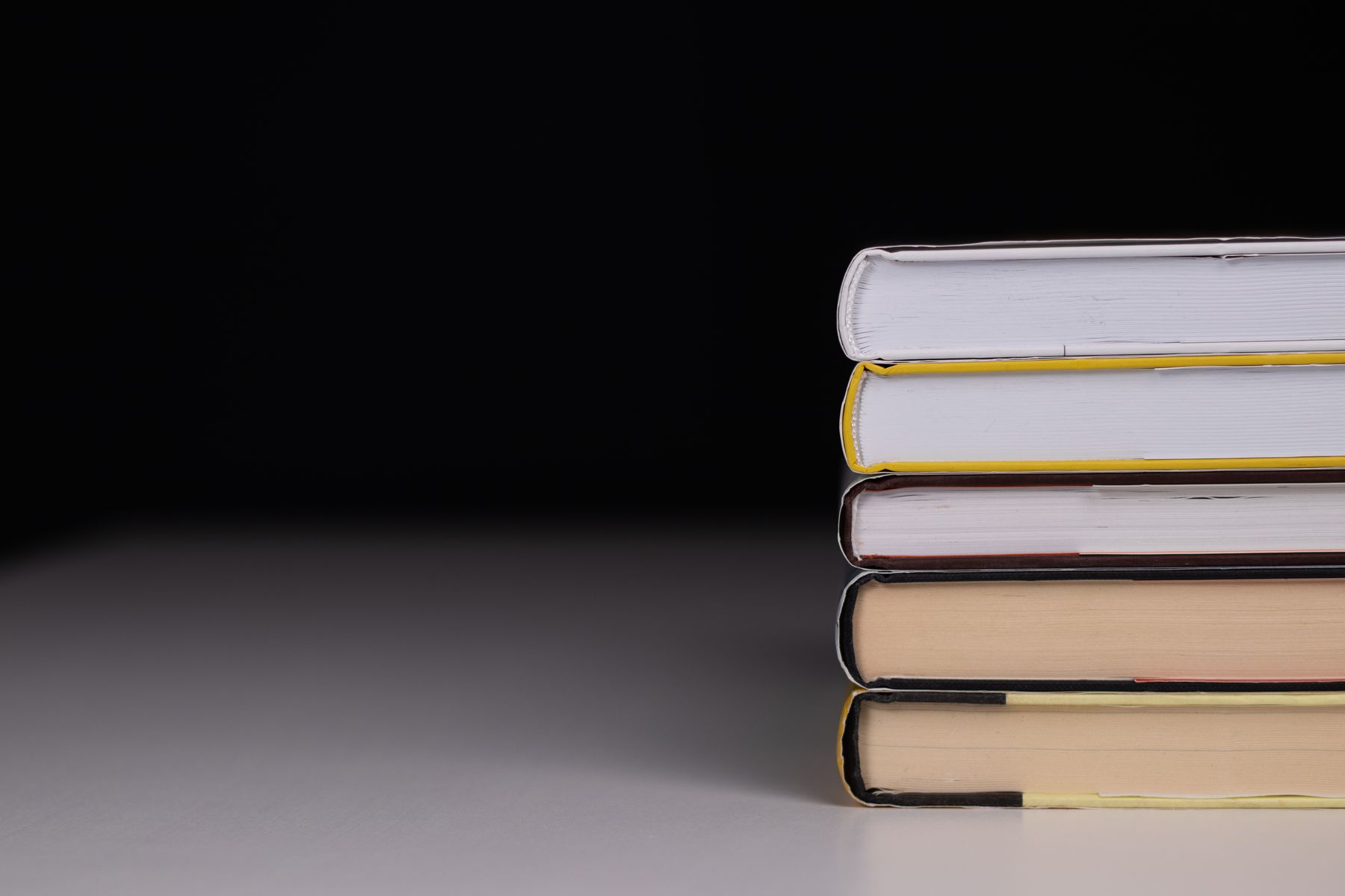 A stack of hardcover volumes lit against a dark ground — photo by dlxmedia.hu on Pexels