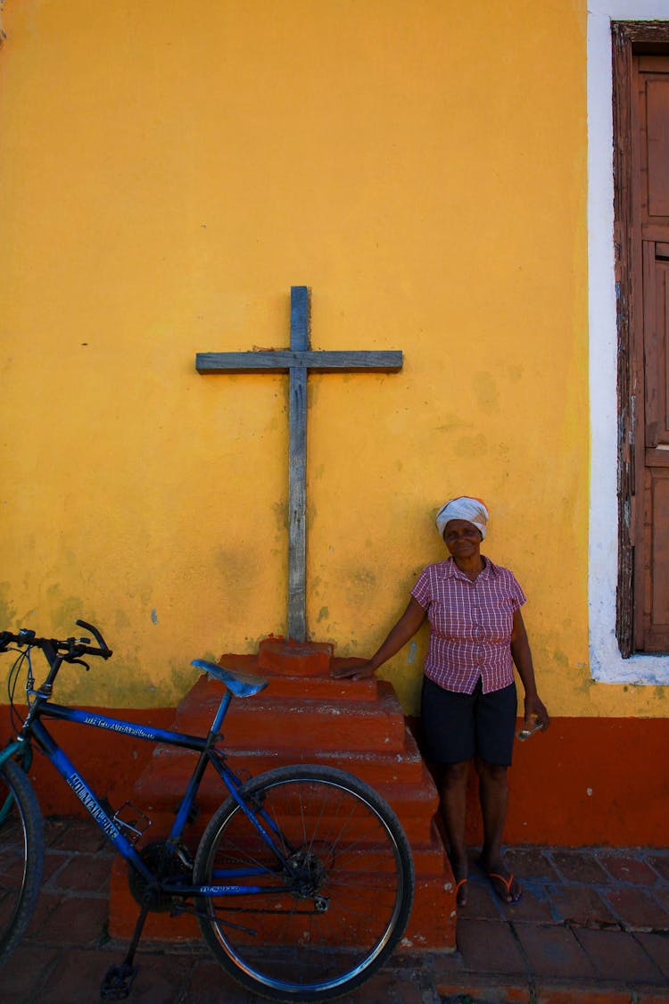 Woman With Bicycle Standing By Cross