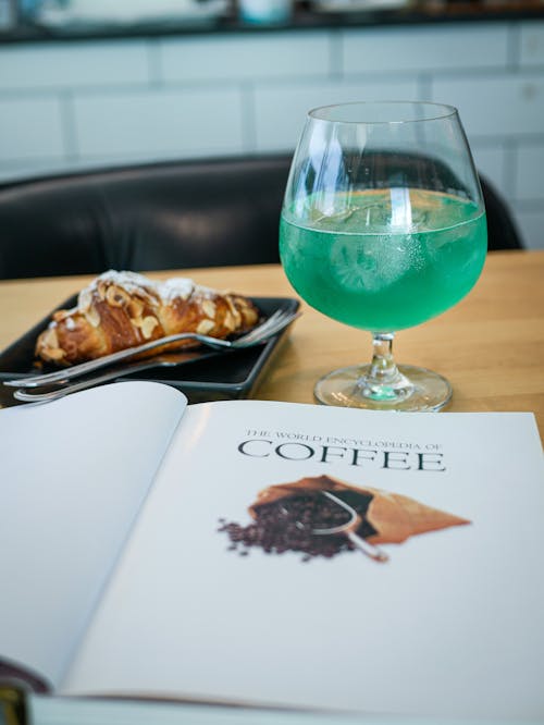 Coffee Magazine Near Glass with Green Liquid and Croissant