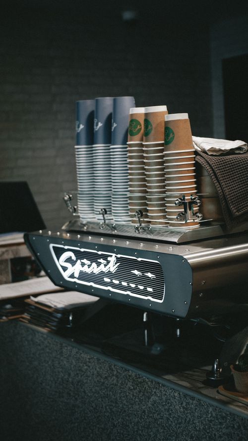 Free Neatly stacked coffee cups on a modern espresso machine in a cozy café setting. Stock Photo