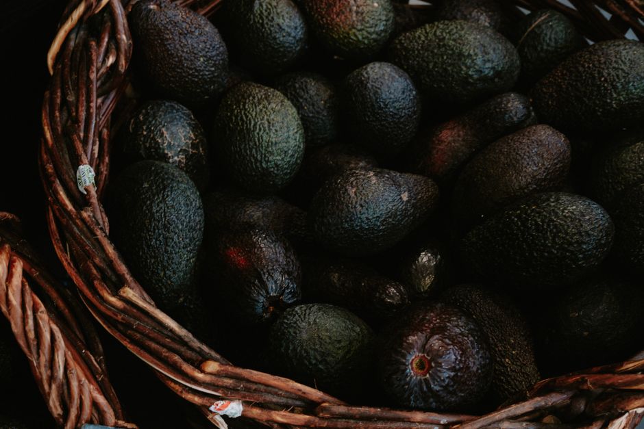 Close-up of fresh avocados in a wicker basket showcasing organic abundance and texture.