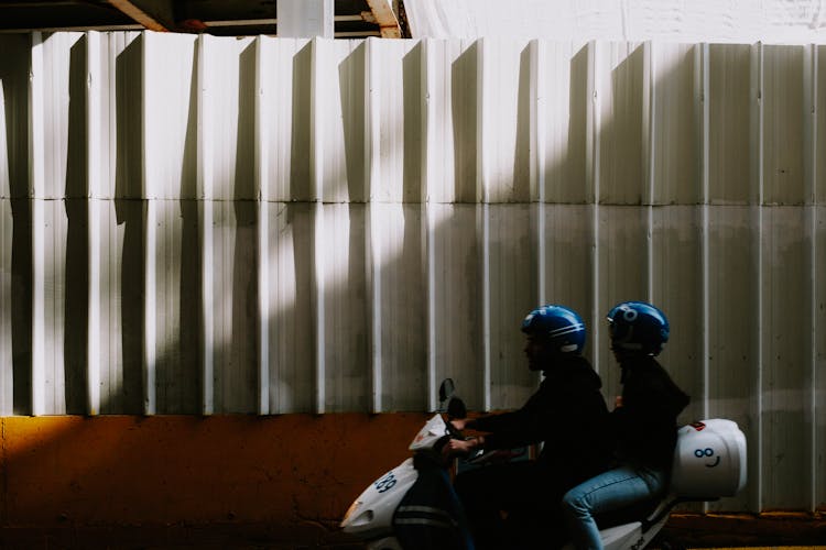 People Wearing Helmet Riding On A Scooter