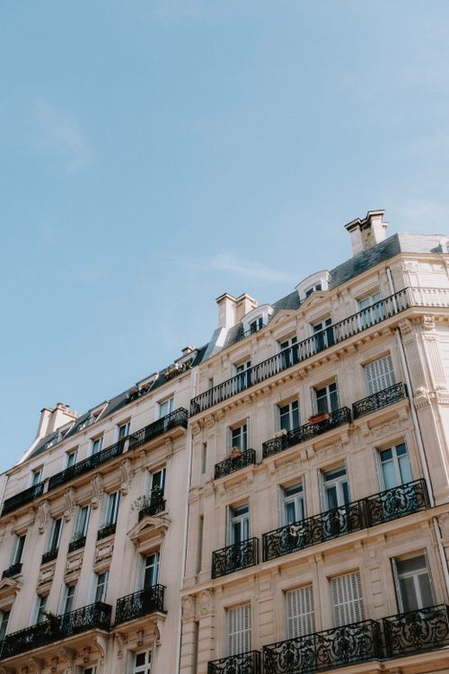 Free Low angle view of Parisian residential building with ornate balconies against a clear blue sky. Stock Photo