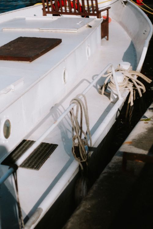 Free Detailed view of a moored boat with nautical ropes and wooden deck in a harbor. Stock Photo