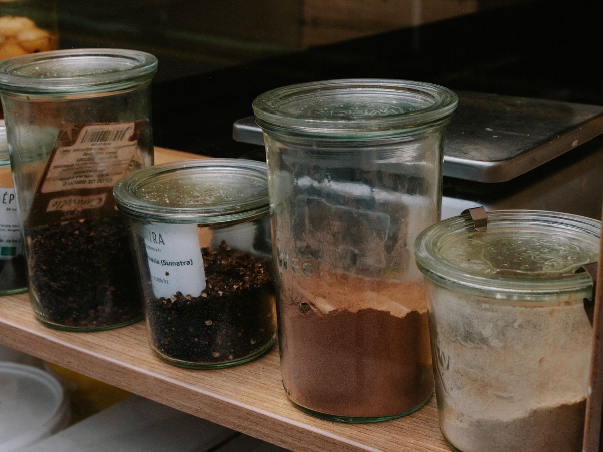Jars of spices lined up on a kitchen shelf, useful for varying flavors across a week of meal prep