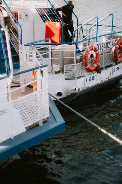 Free A ferry moored at the harbor with a man handling ropes, ready for departure. Stock Photo