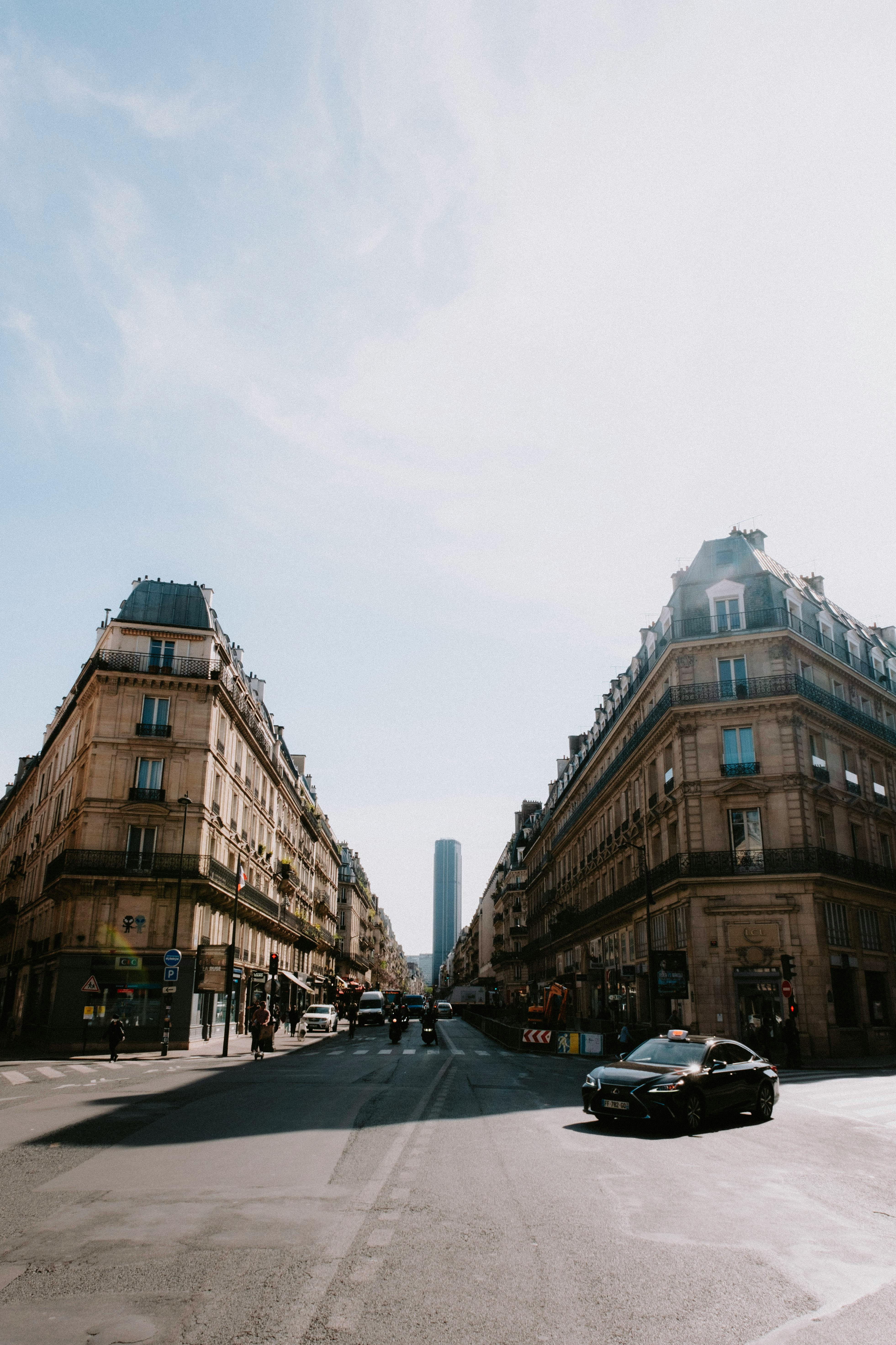 Parisian street scene with classic architecture and morning sunlight, showcasing urban life.
