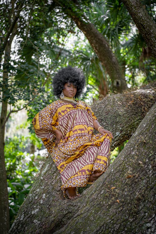 A Woman Wearing an Animal Print Dress Posing while on a Tree Trunk