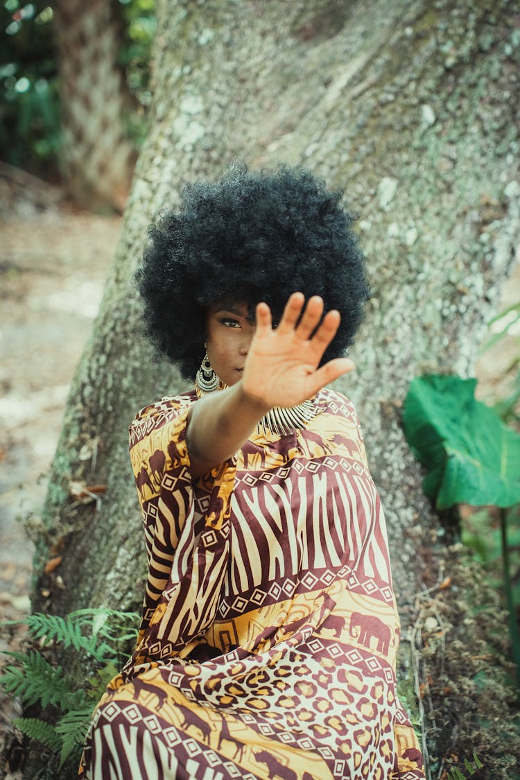 Woman In Animal Print Dress Sitting On A Tree Trunk