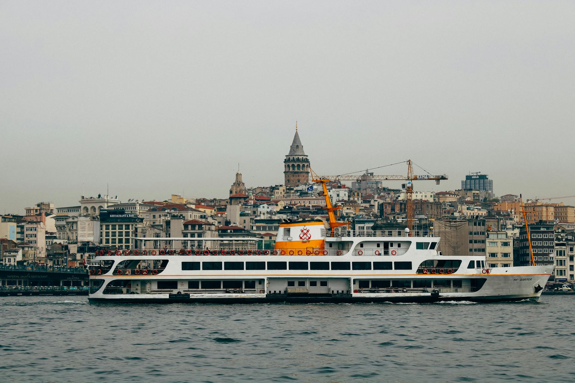 A ferry cruises past the historic Galata Tower on the Bosphorus in Istanbul, Turkey.
