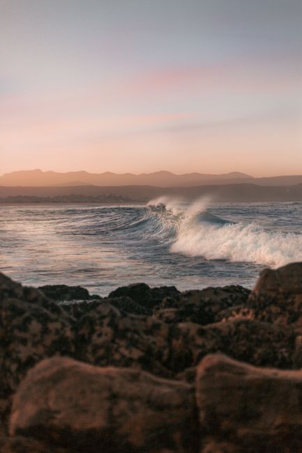 Captivating sunset at Plettenberg Bay with waves crashing onto rocky shores.