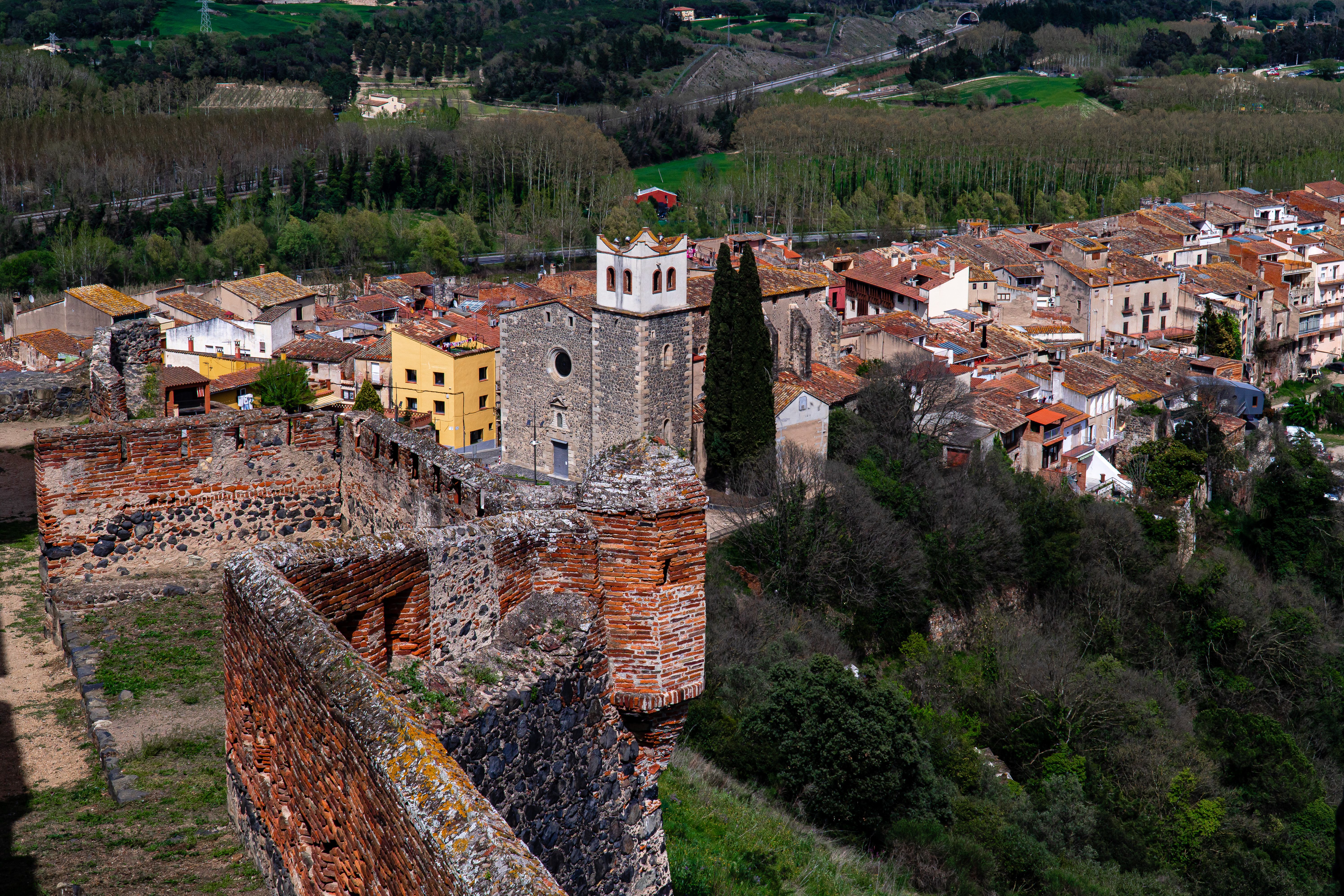 A breathtaking view of an ancient ruin and a picturesque town, surrounded by lush countryside landscape.