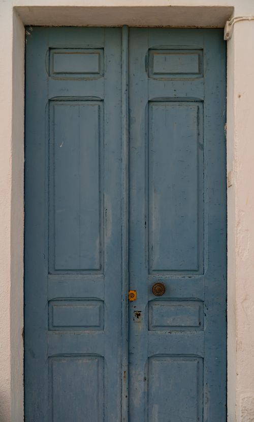 Free A rustic blue wooden door set into a white classic building facade, style emphasizes vintage charm. Stock Photo